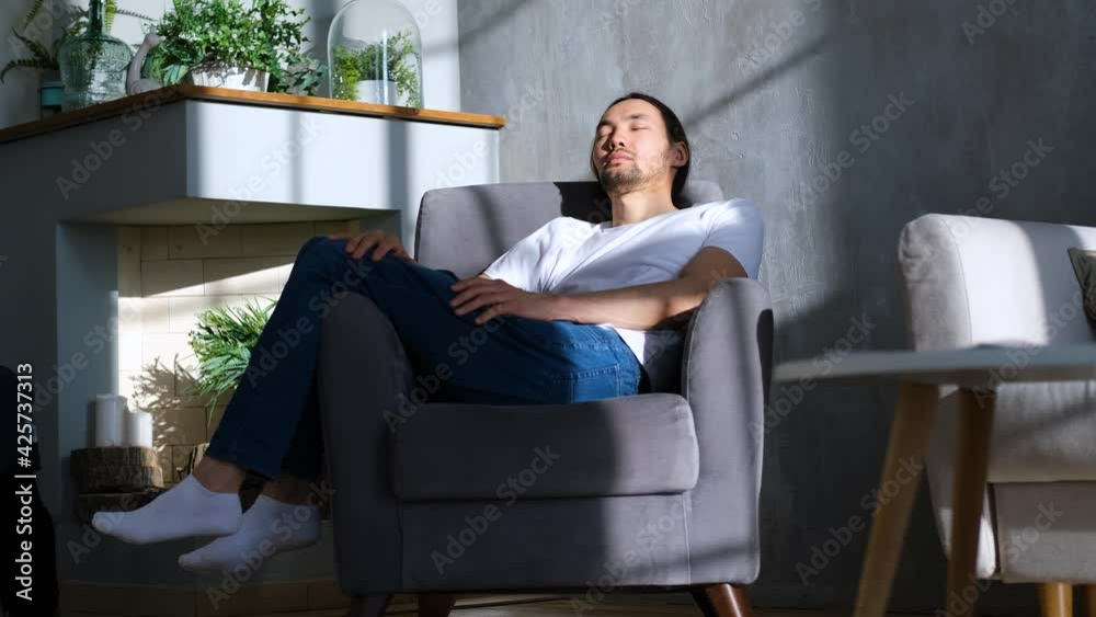 young asian man resting in a chair in the sun young asian man resting in a chair in the sun