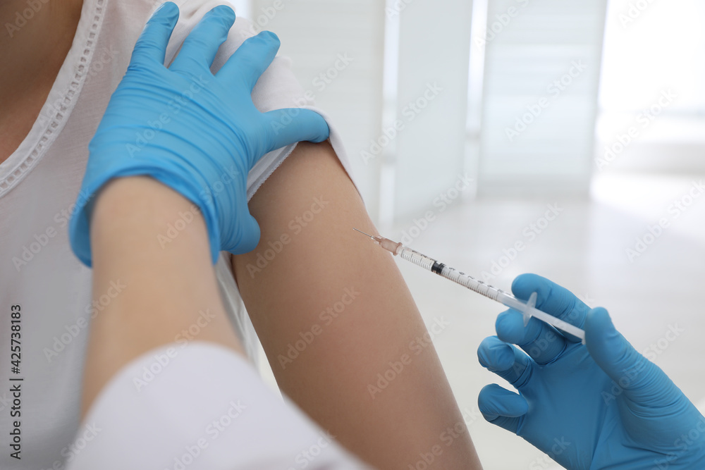 Doctor giving injection to woman in hospital, closeup. Immunization concept Doctor giving injection to woman in hospital, closeup. Immunization concept