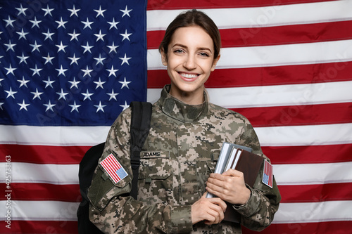 Female cadet with backpack and books against American flag. Military education