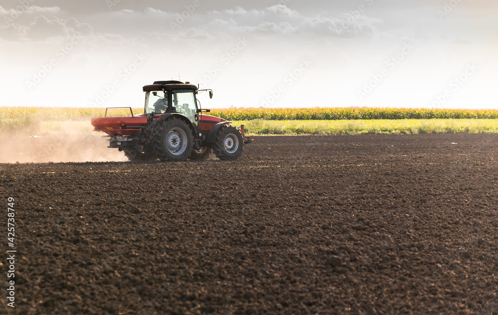 Fototapeta premium Tractor spreading artificial fertilizers in field