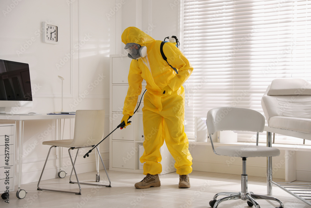 Man in protective suit sanitizing doctor's office. Medical disinfection Man in protective suit sanitizing doctor's office. Medical disinfection