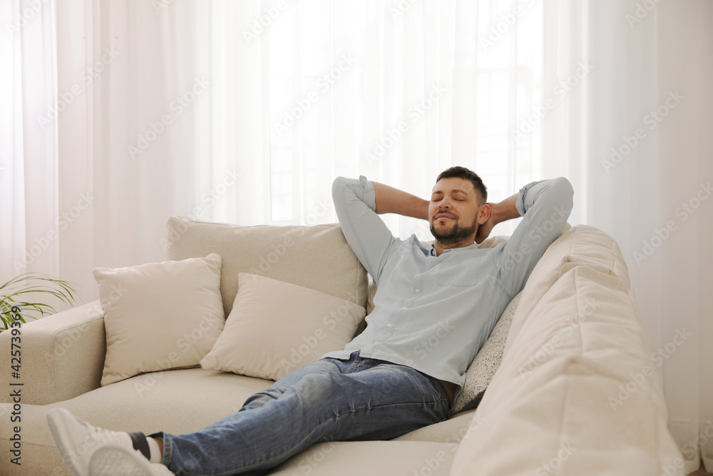 Man resting on comfortable sofa in living room