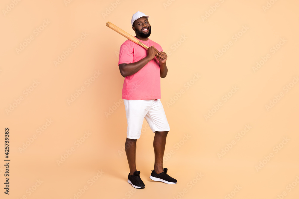 Full length body size photo of man keeping wooden bat wearing t-shirt shorts isolated on pastel beige color background Full length body size photo of man keeping wooden bat wearing t-shirt shorts isolated on pastel beige color background