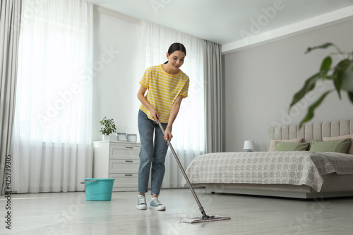 Woman cleaning floor with mop at home