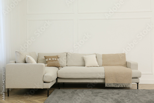 Comfortable sofa near white wall in living room