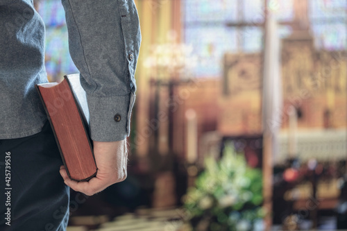 Man holding holy bible in church with alter in background photo