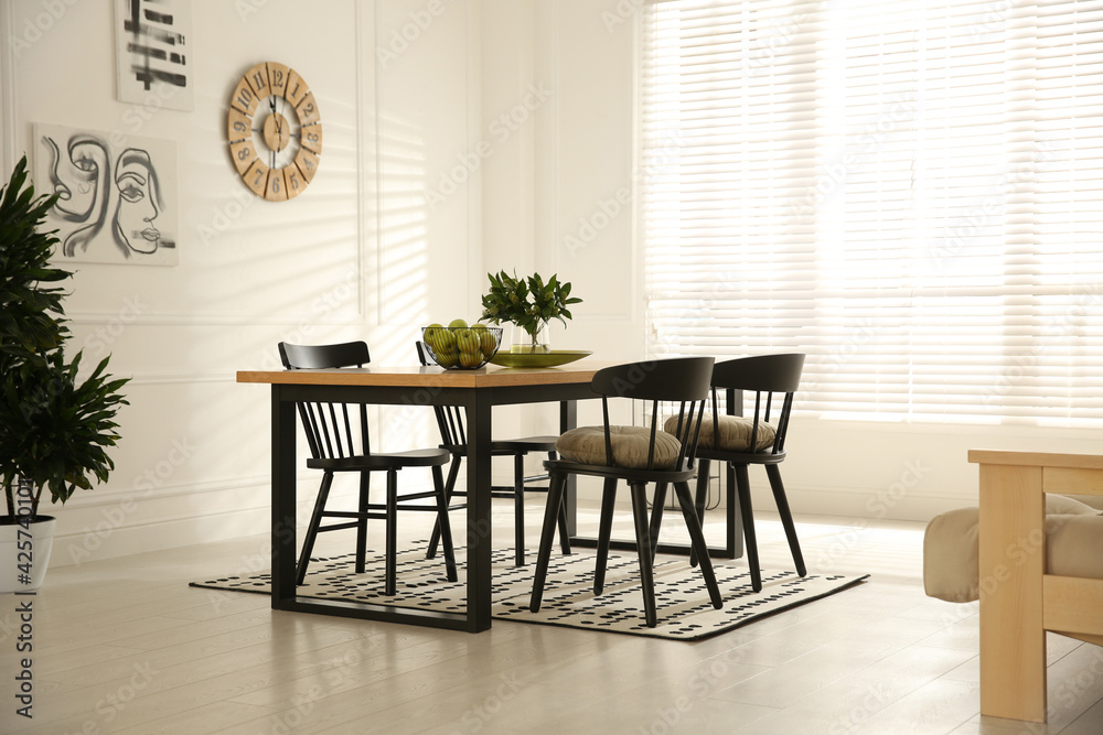 Stylish wooden dining table and chairs in room. Interior design Stylish wooden dining table and chairs in room. Interior design