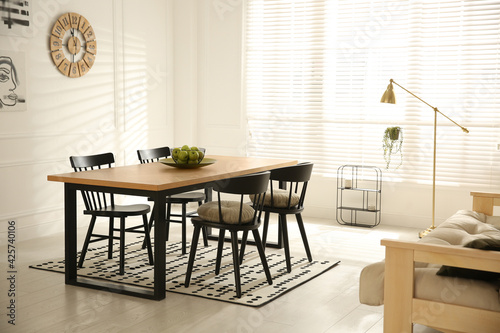 Stylish wooden dining table and chairs in room. Interior design © New Africa