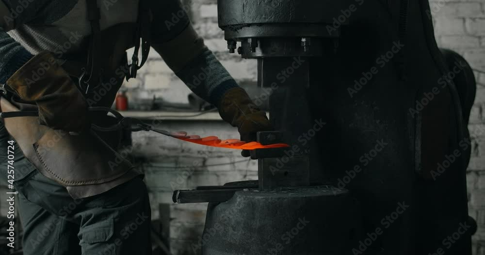 Blacksmith makes a decorative red-hot forged metal product with hydraulic hammer, blacksmith's workshop, 4k 60p Prores HQ Blacksmith makes a decorative red-hot forged metal product with hydraulic hammer, blacksmith's workshop, 4k 60p Prores HQ