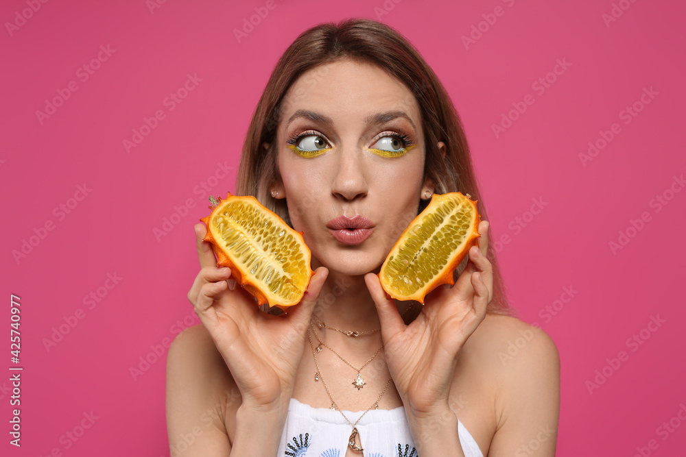 Young woman with fresh kiwano on pink background. Exotic fruit Young woman with fresh kiwano on pink background. Exotic fruit