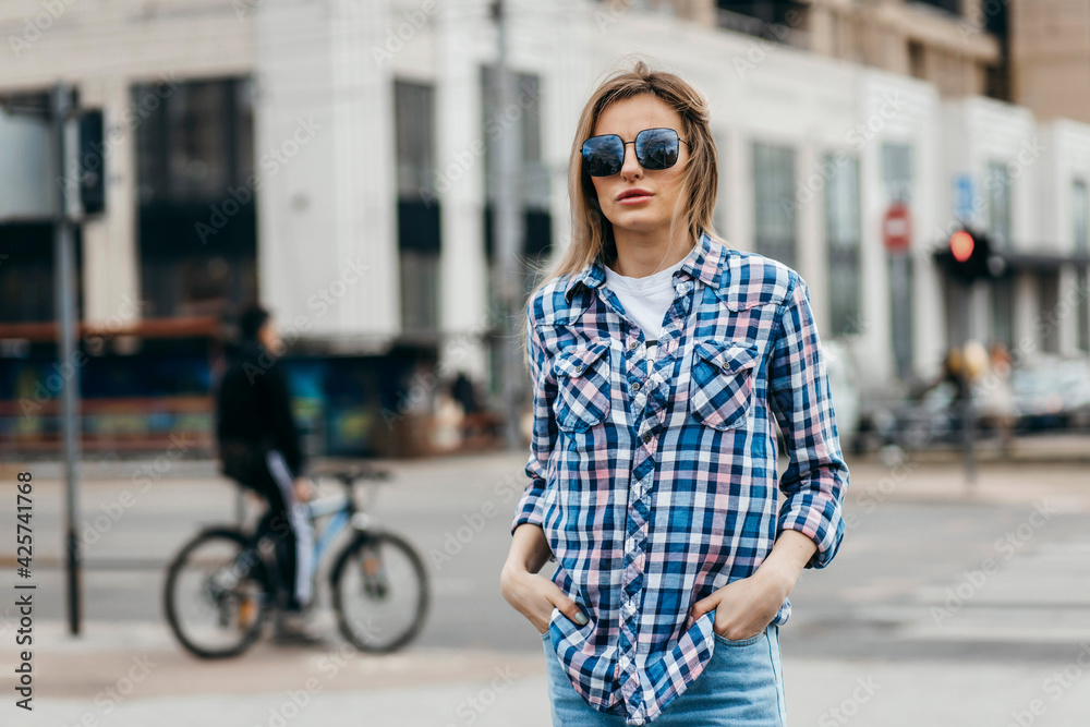 Fashion portrait of beautiful woman with beautiful face, wearing grunge plaid shirt. Posing alone.