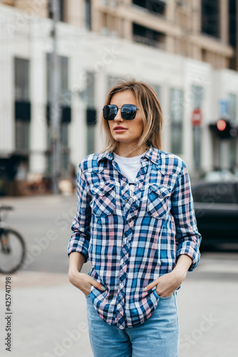 Fashion portrait of beautiful woman with beautiful face, wearing grunge plaid shirt. Posing alone.