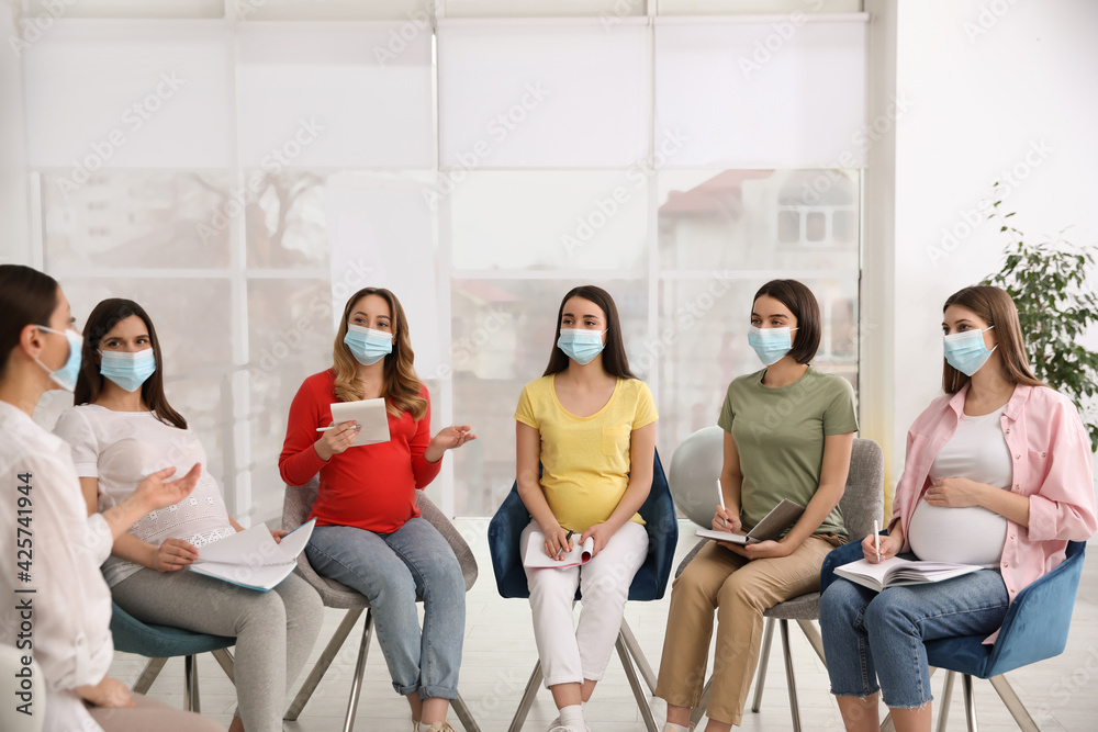 Fototapeta premium Group of pregnant women and midwife in protective masks at courses for expectant mothers indoors