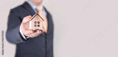 businessman holding model house on his hand. banner. Concept: real estate investment and mortgage, home construction, purchase. copy space