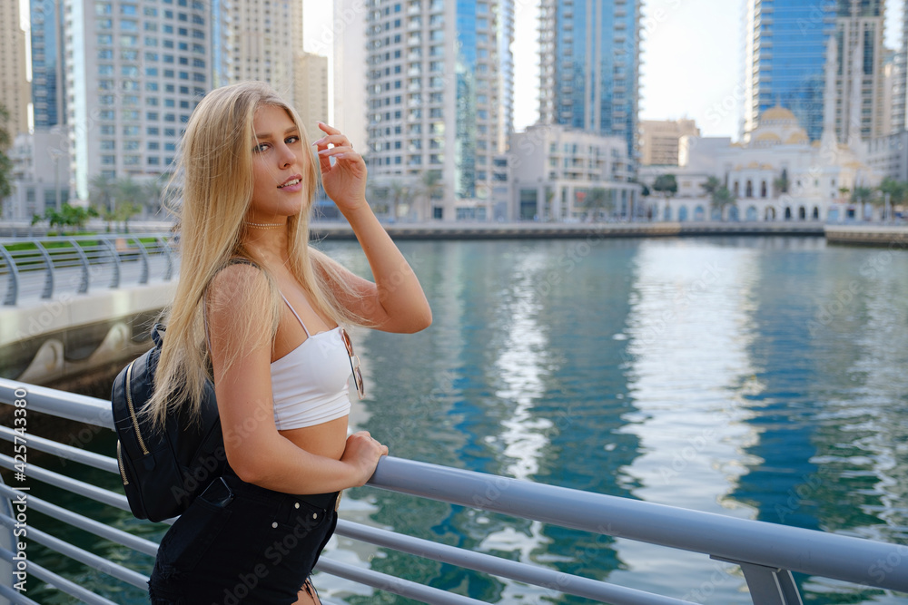 Young blonde travel woman walking on the street outdoors in Dubai city