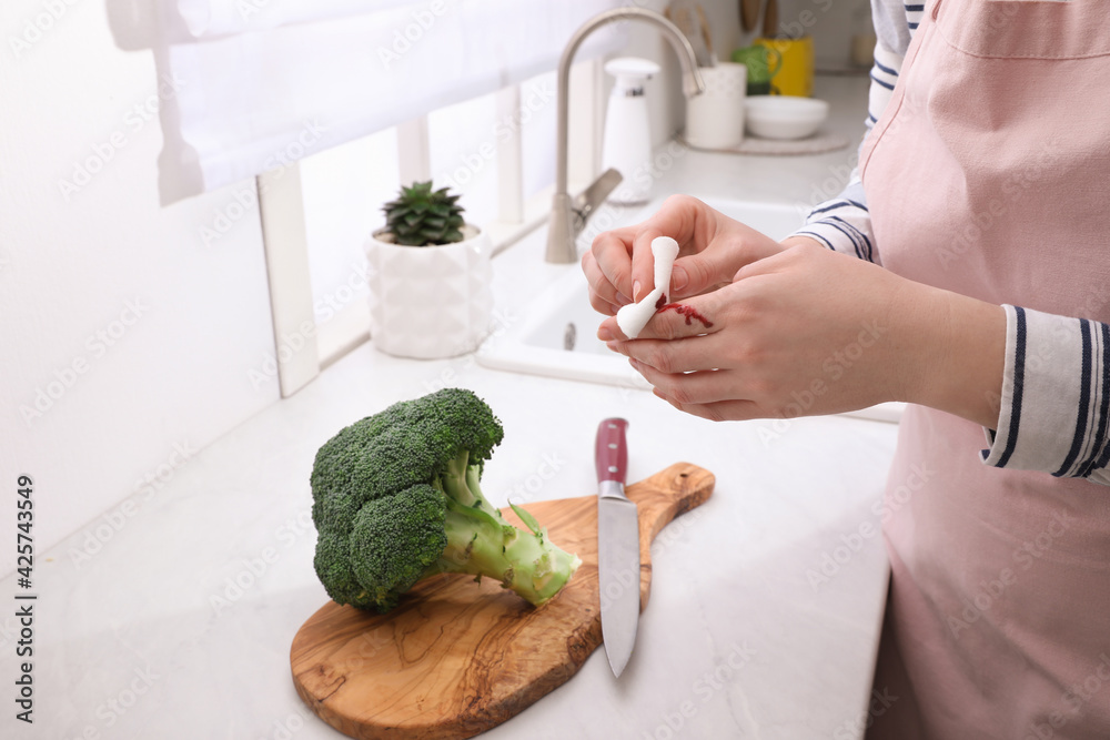 Woman cut finger while cooking in kitchen, closeup