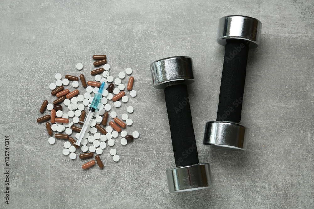 Different drugs and sports equipment on grey table, flat lay. Doping control Different drugs and sports equipment on grey table, flat lay. Doping control