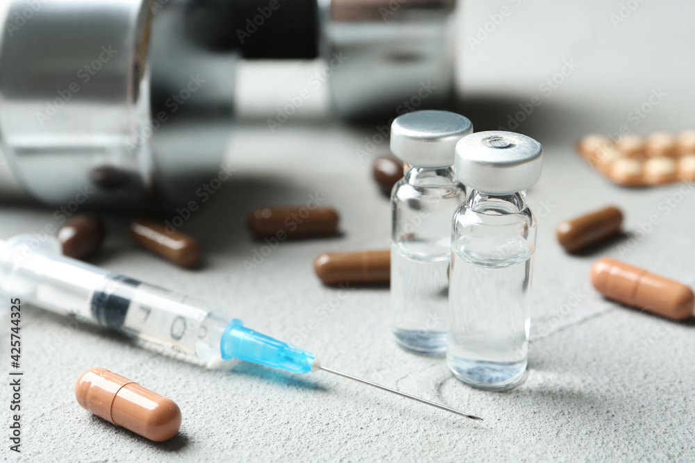 Different drugs and dumbbells on light grey table. Doping control Different drugs and dumbbells on light grey table. Doping control