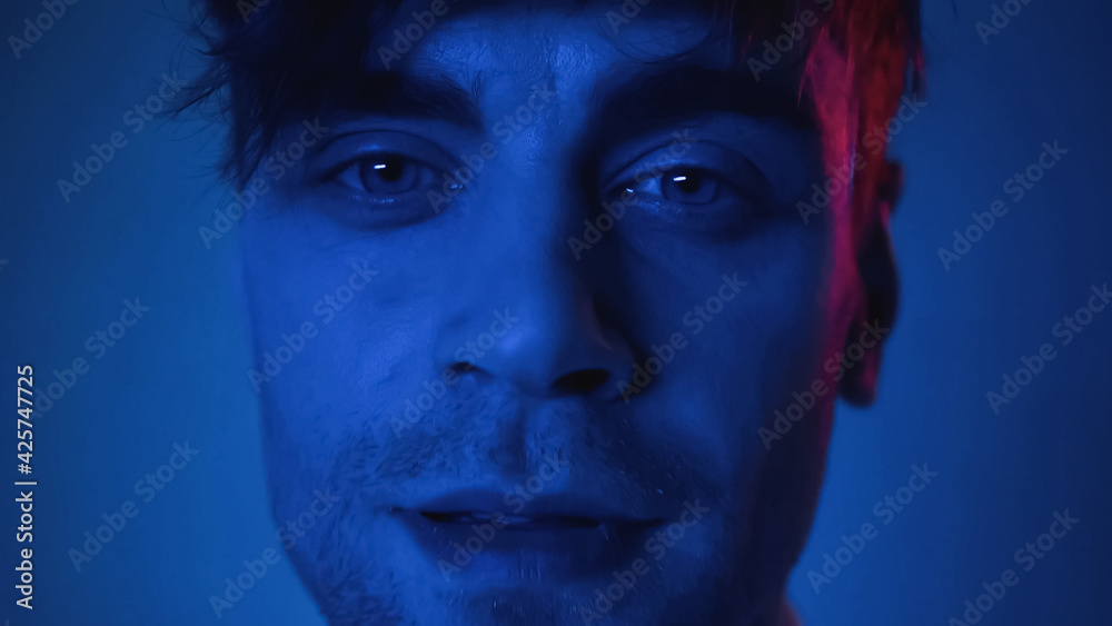 close up of man looking at camera on blue