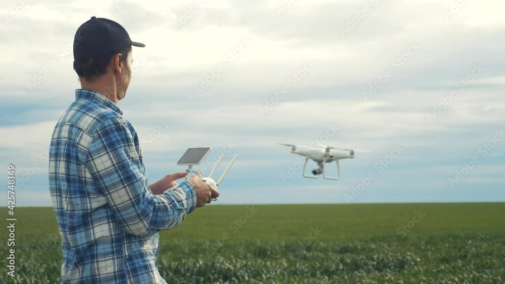smart farming tech agriculture farming. man farmer engineer studies a wheat lifestyle crop in a green field using a technology quadcopter. male red worker neck works in a green field in a field of smart farming tech agriculture farming. man farmer engineer studies a wheat lifestyle crop in a green field using a technology quadcopter. male red worker neck works in a green field in a field of