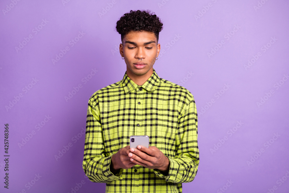 Portrait of attractive focused serious guy holding in hands using gadget browsing web wi-fi isolated over violet purple color background Portrait of attractive focused serious guy holding in hands using gadget browsing web wi-fi isolated over violet purple color background