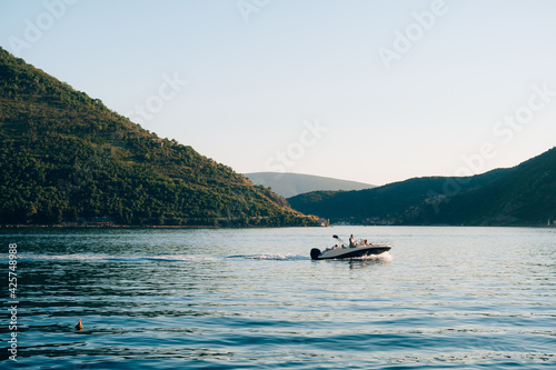 Fototapeta Naklejka Na Ścianę i Meble -  A motor boat with people on board is sailing along the Bay of Kotor.