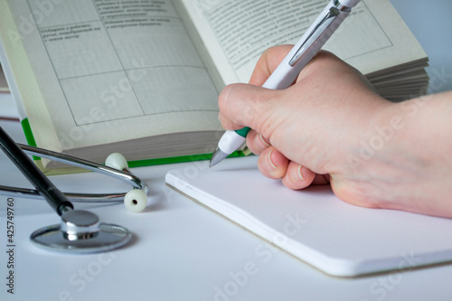 Medical concept. On the table are a stethoscope, a pen, a notebook, a book. Medical background on a white background. Preparation for the examination, compendium