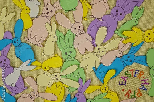 Multicolored Easter bunnies from colored paper on a white burlap, background