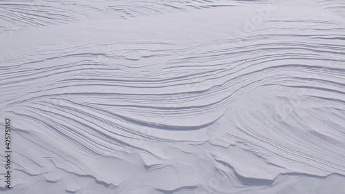 Curved lines and layers in pure white snow abstract textured background