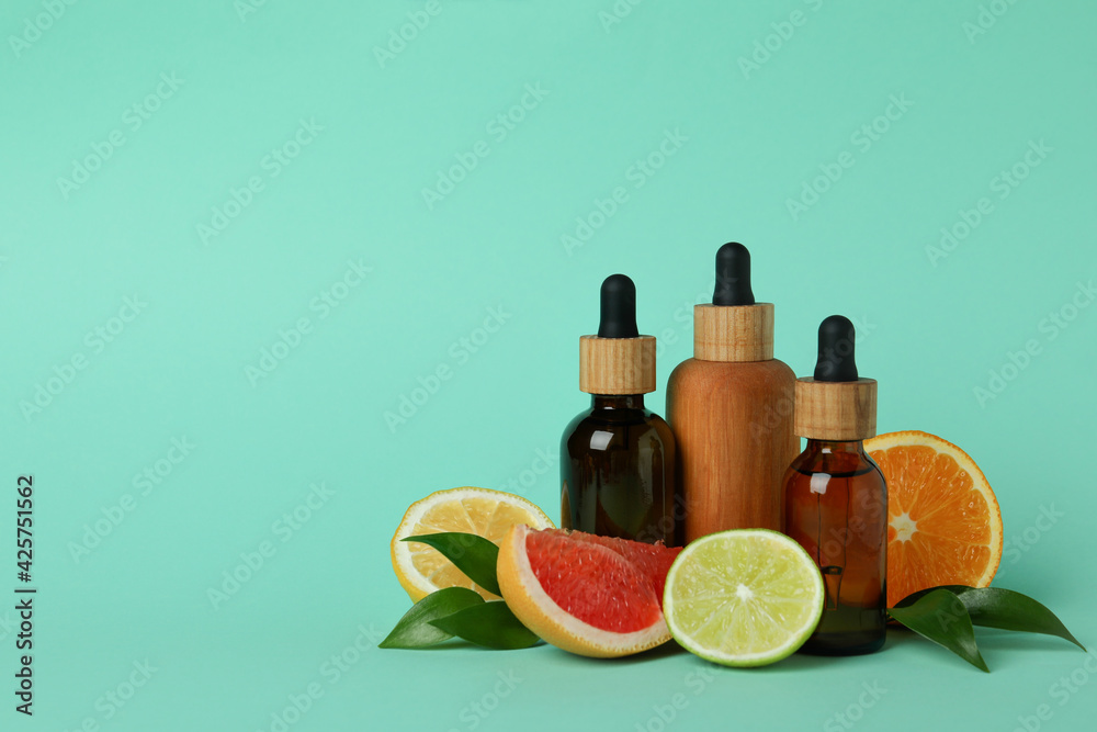 Dropper bottles with oil and citrus on mint background