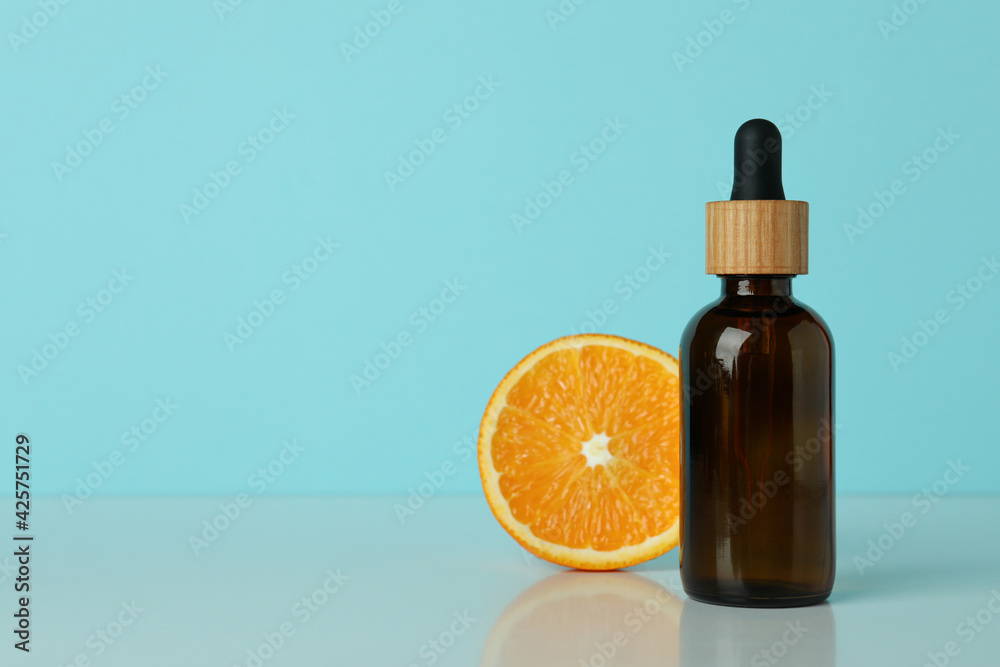 Dropper bottle with oil and orange against blue background Dropper bottle with oil and orange against blue background