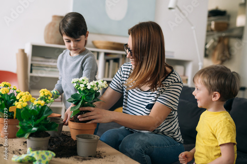 mother gardening houseplants with her kids at home