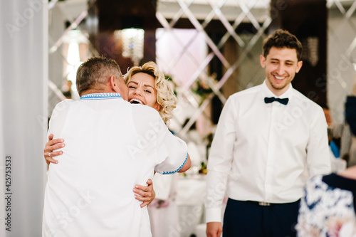 Dad congratulates the brides with a marriage and hugs. man welcomes. Happy bride and groom. Wedding ceremony. Close up photo