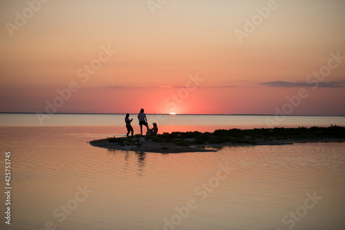 silhouette of a couple on the beach. three silhouettes at sunset in the middle of the lake 