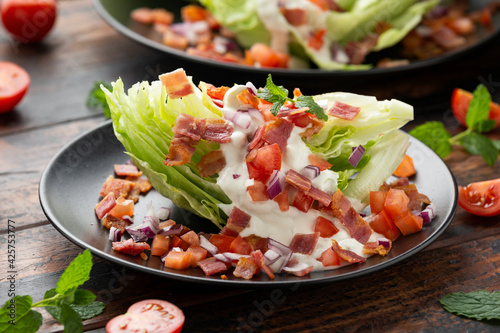 Obraz na plátne Iceberg wedge salad with bacon, cherry tomatoes, red onion and dressing