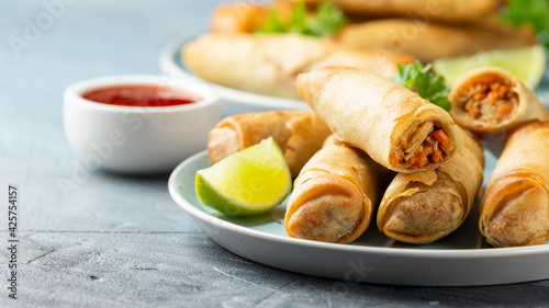 Fried spring rolls with sweet chili sauce and lime on plate photo