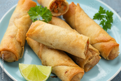 Fried spring rolls with sweet chili sauce and lime on plate