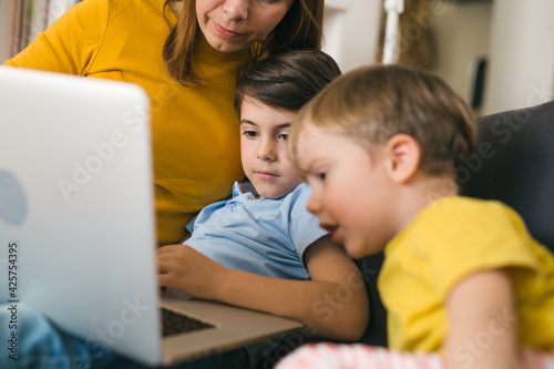 mother using laptop computer with her kids