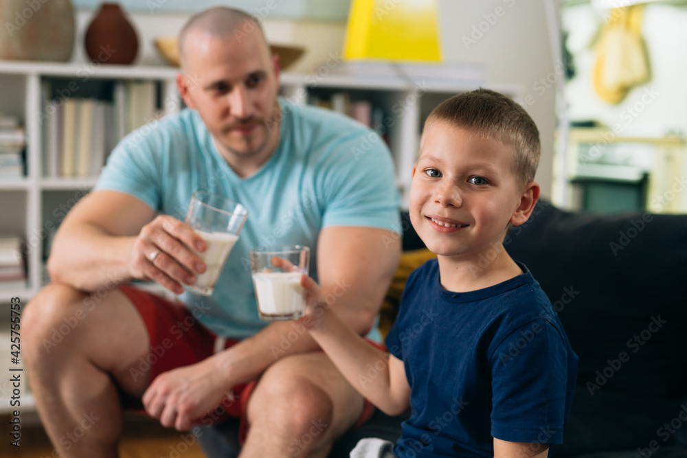 Obraz premium father and son exercise at home. drinking milk after training