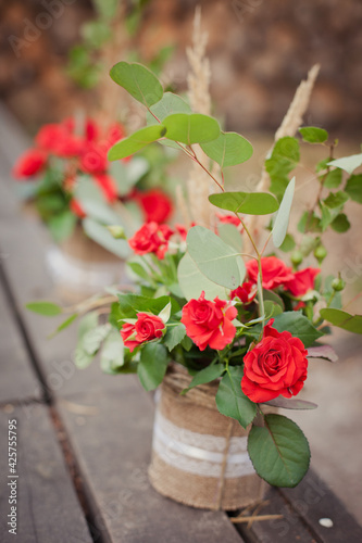 Fototapeta Naklejka Na Ścianę i Meble -  Decorations in rustic style: beautiful bouquets from red roses in a flowerspot decorated by sackcloth