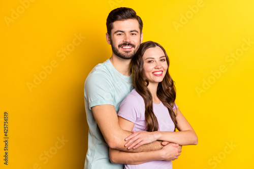 Portrait of attractive cheerful couple embracing spending day time honeymoon holiday isolated over bright yellow color background