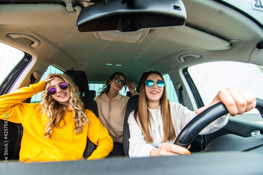Three female friends in sunglasses enjoying traveling at vacation in the car.