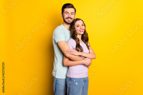 Portrait of attractive gentle cheerful couple embracing honeymoon day isolated over bright yellow color background