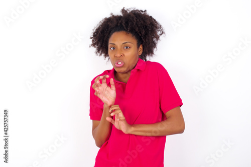 Ugh how disgusting! Displeased young beautiful African American woman wearing pink t-shirt against white wall , has dissatisfied facial expression as sees something abominable.