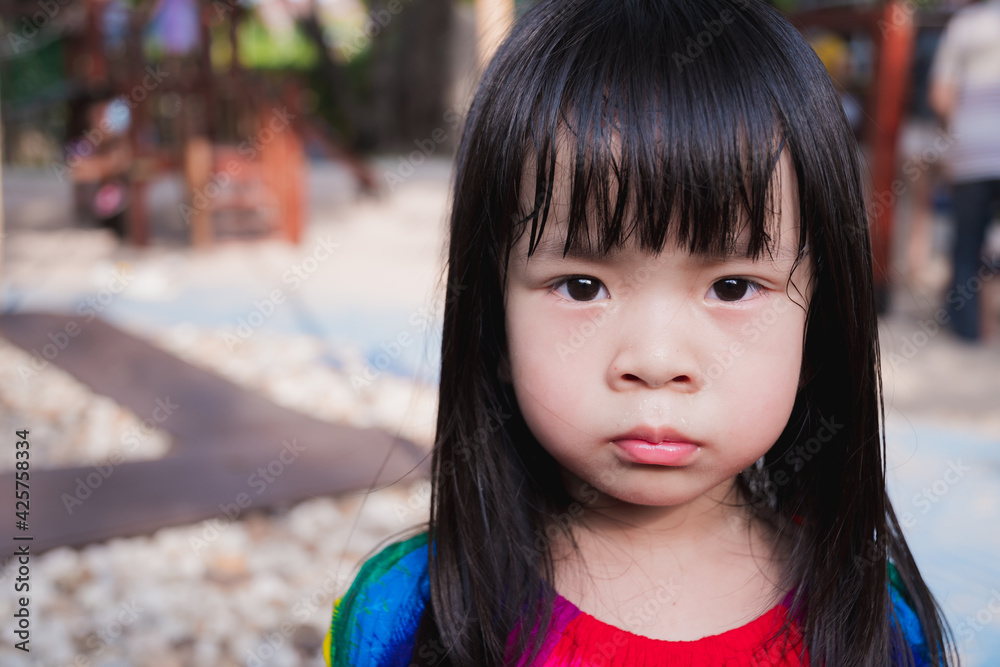 Closeup face child is hot sweat. Upset girl in the playground outside. Kid black haired unhappy when hot weather. Baby wear colorful dress aged 4 years old. In summer or spring time. Closeup face child is hot sweat. Upset girl in the playground outside. Kid black haired unhappy when hot weather. Baby wear colorful dress aged 4 years old. In summer or spring time.