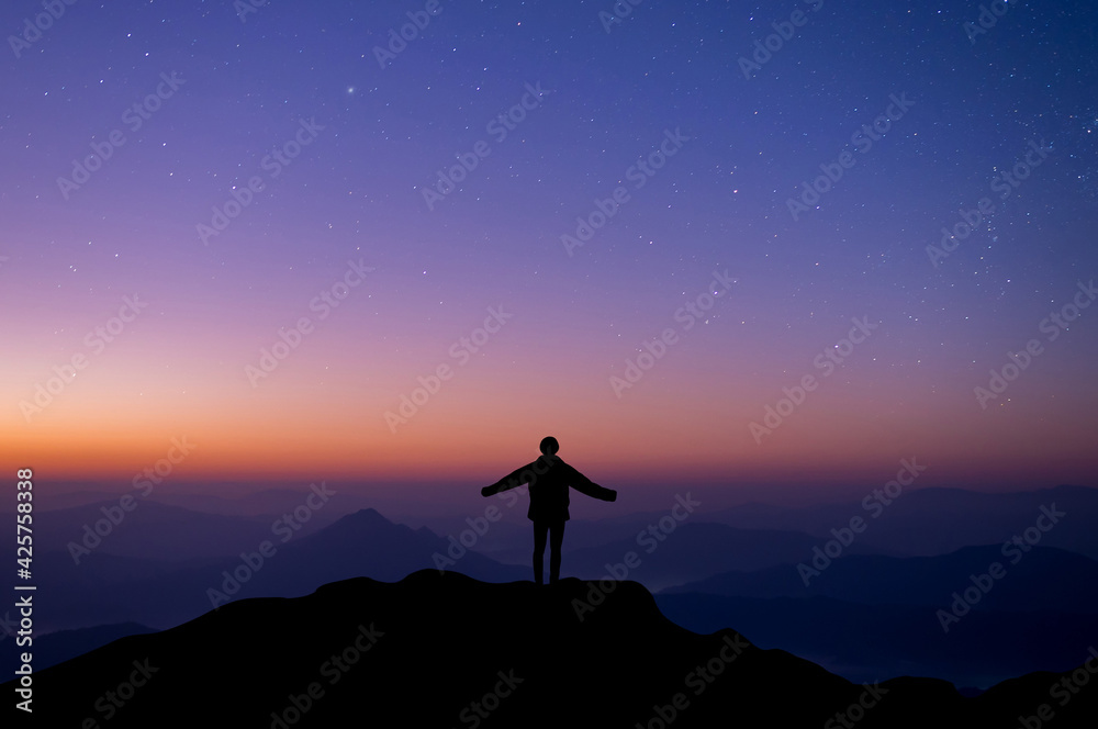 Silhouette of happy woman open hands against and watched night sky, star and milky way background alone on top of the mountain. People having fun on summer vacation  freedom and imagination concept.