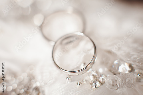 Two wedding rings on background of wedding dress