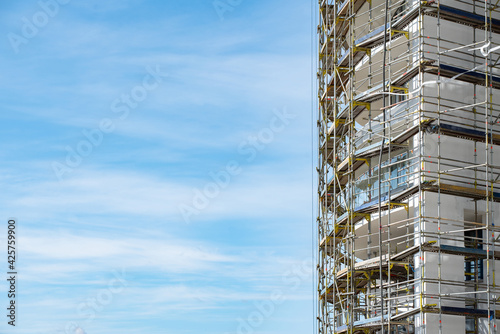 Big metal scaffolding on the facade of an apartment building against the sky outside 
