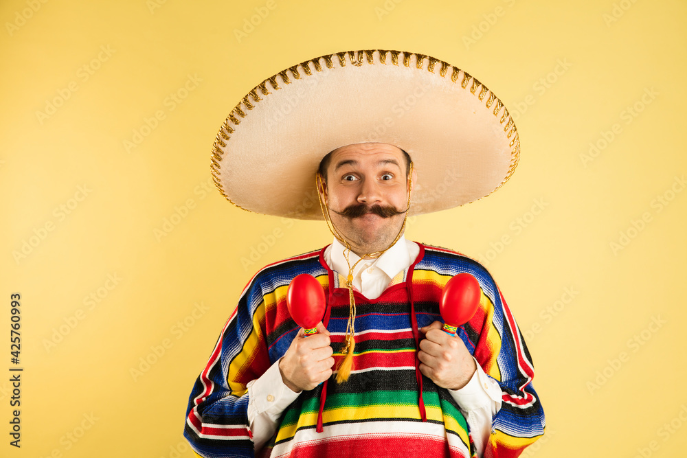 Happy man in sombrero and bright poncho isolated over yellow background  Photos | Adobe Stock