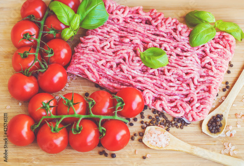 Ingredients for Lasagna or Bolognese Sauce .Pork Mince ,Cherry Tomatoes and Basil on a Wooden Background 